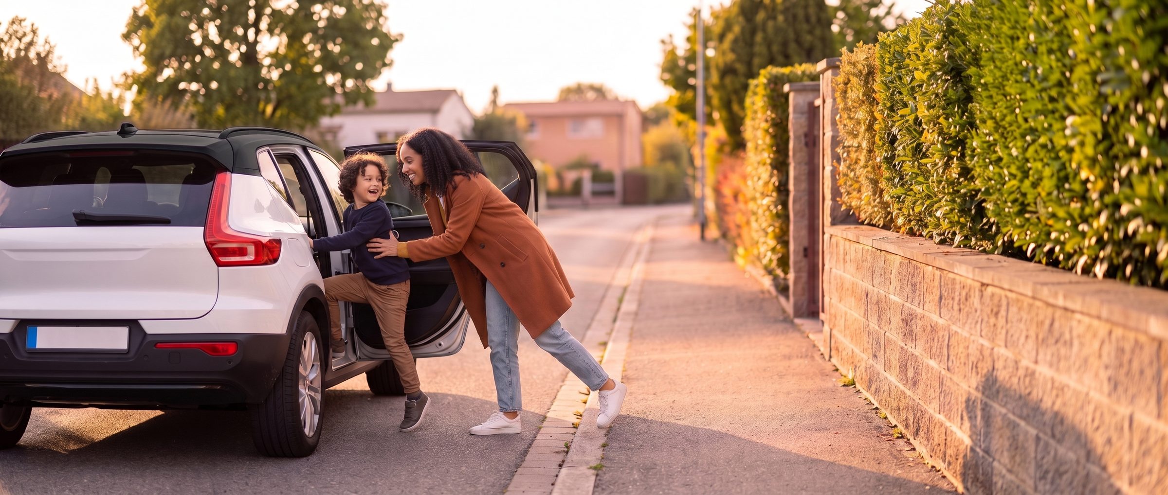 Una collega apre la portiera posteriore della sua auto al figlio; ridono entrambi